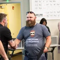 A student apprentice receives his certificate from instructors after finishing his program of study.