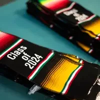 A stack of multi-colored stoles that read "Class of 2024" lay on a table.