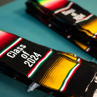 A stack of multi-colored stoles that read "Class of 2024" lay on a table.
