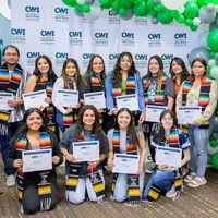 A group of 12 graduating students holding certificates and 2 teachers pose of a photo. 