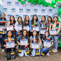 A group of 12 graduating students holding certificates and 2 teachers pose of a photo. 