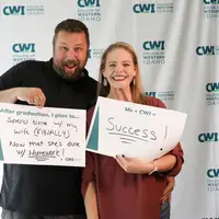 Graduate with spouse holding signs