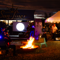 Bonfire surrounded by people, tents, and projections