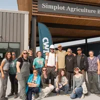 Group of people posing and smiling in front of the Simplot Agriculture Building at College of Western Idaho.