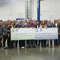 Groups of people standing together holding two checks