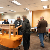 People talking and standing in front of wood structure 