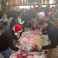 People surronding table, wrapping presents