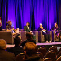 Group of people sit in chairs on stage