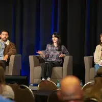 Students sit in chairs on a panel on stage