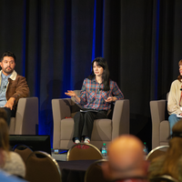 Students sit in chairs on a panel on stage