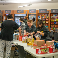Students hover over table to collect items and fill bags with food and hygiene products
