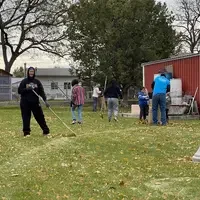 Volunteers raking up leaves in a lawn