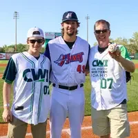 Three people on the baseball field posing for picture