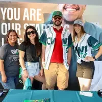 Four people posing for picture with winning baseball jersey