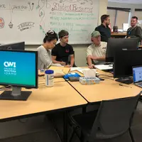 Students and staff working at a computer