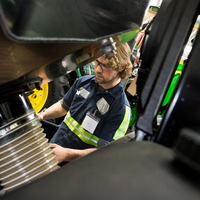 A student performs maintenance on a tractor.