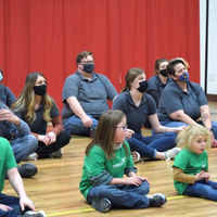 Kids and students sitting on the floor listening