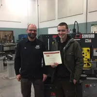 Student standing holding a Emerging Professionals certificate and standing next to instructor