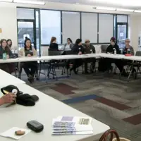 Participants sitting at tables listening at the Native American Beading Workshop