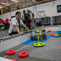 A robot navigates an obstacle course during a robotics competition with participants observing..