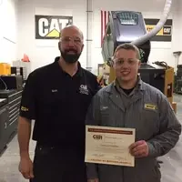 Student standing holding a Emerging Professionals certificate and standing next to instructor