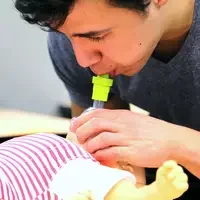 EMS student Daniel Sandoval practices rescue breaths on an infant-sized manikin.