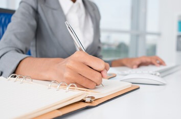 Woman writing in notepad at a desk
