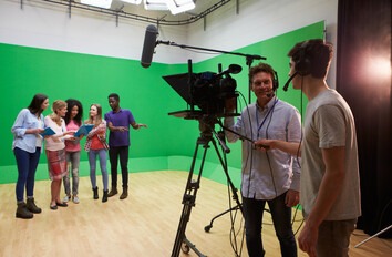 Media arts students recording a video of a group of students with a green screen
