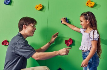 Occupational Therapy Assistant student working with young girl on climbing wall
