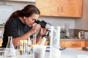 Student looking through microscope in classroom lab