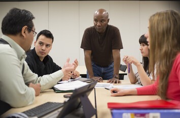 Management students having a discussion around a table in a classroom