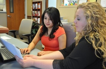 Medical administrative assistant students reviewing paper work at a desk