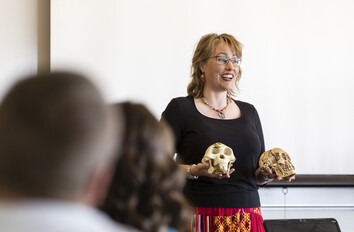 CWI instructor holding two skulls speaking to a class