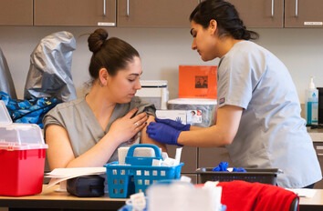 Medial Assistant students in lab practicing giving shots to patient