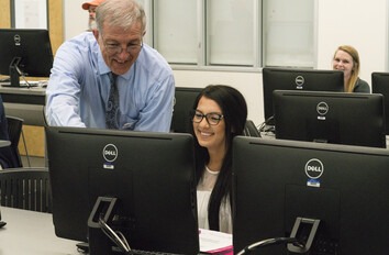 Instructor helping student at computer in classroom