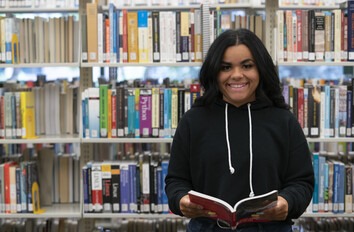 CWI student holding a book in the library