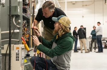 CWI student and instructor at a piece of equipment with a meter
