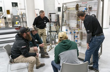 Instructor showing group of students components on an HVAC system