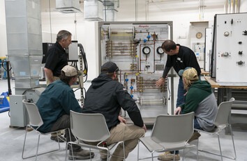 Instructor showing group of students components on an HVAC system