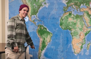 Student standing in front of world map