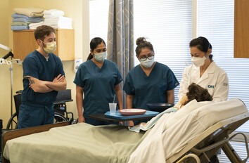 Hemodialysis Technician students in healthcare lab standing around patient's bed