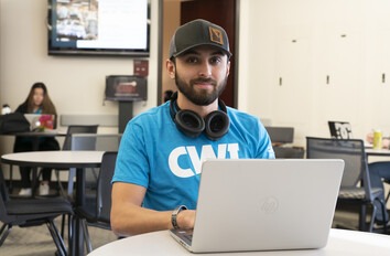 CWI student sitting at a table with a laptop