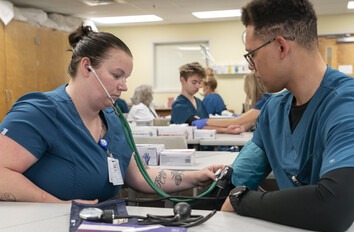 Two CWI students in a medical classroom using blood pressure equipment