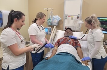 Group of CWI students in scrubs over a mannequin