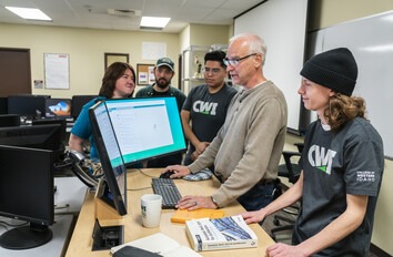 CWI students and instructor gathered around a computer