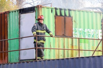Person in fire suite standing on large container