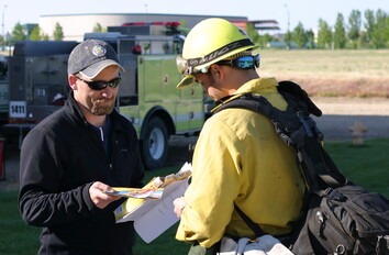 Instructor and student talking outside next to Wildland Fire truck