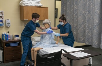 Students in healthcare lab working with a patient on hospital bed