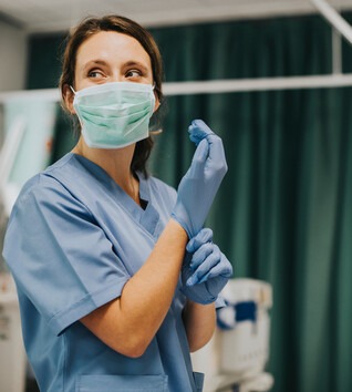 Nurse in a hospital setting putting on a glove