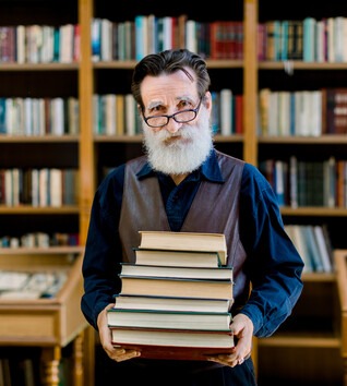 History professor with pile of books in library